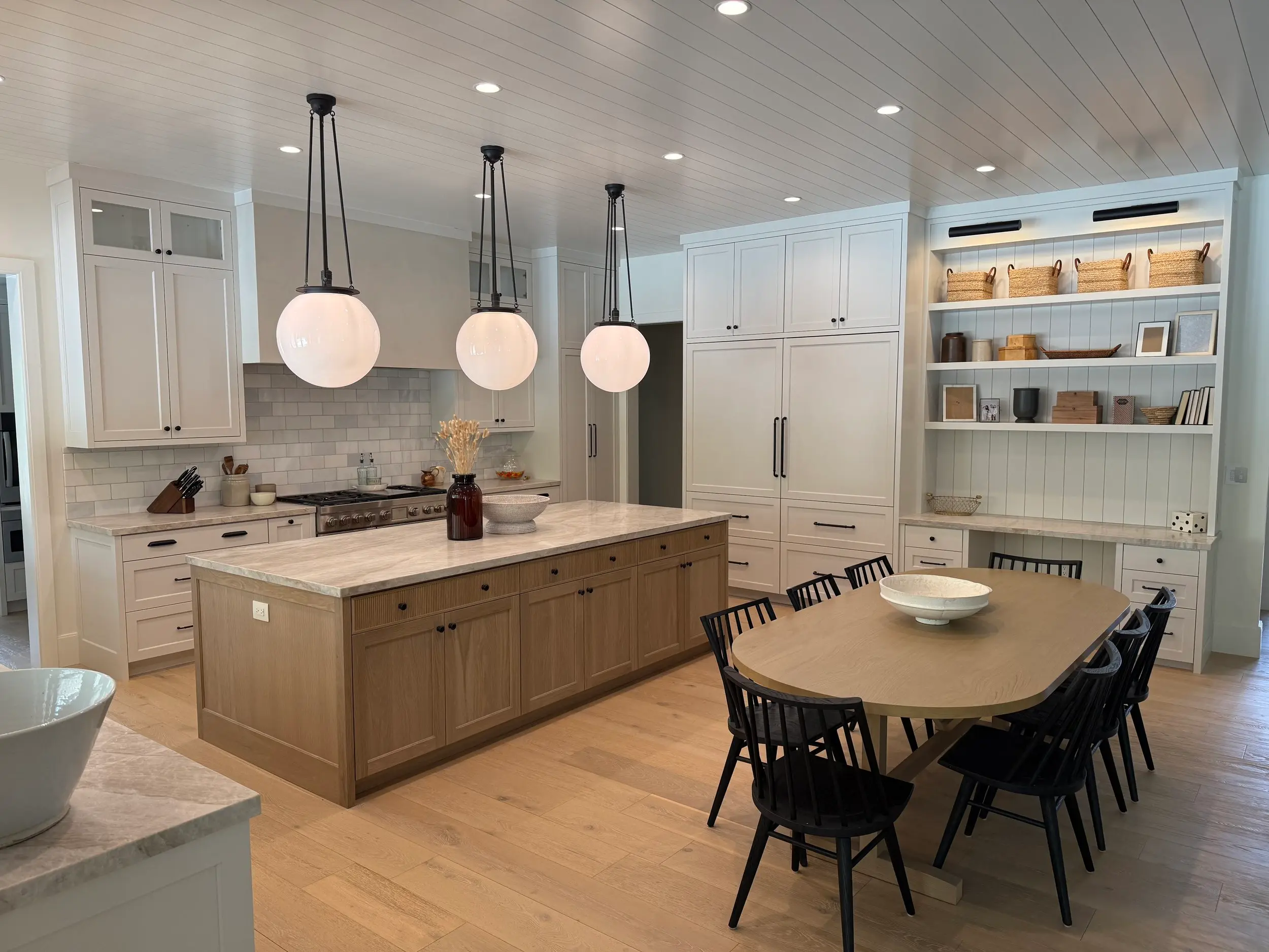 Custom-built kitchen island with hand-finished wood cabinetry, marble waterfall countertop, and matte black faucet — bespoke cabinet shop craftsmanship.