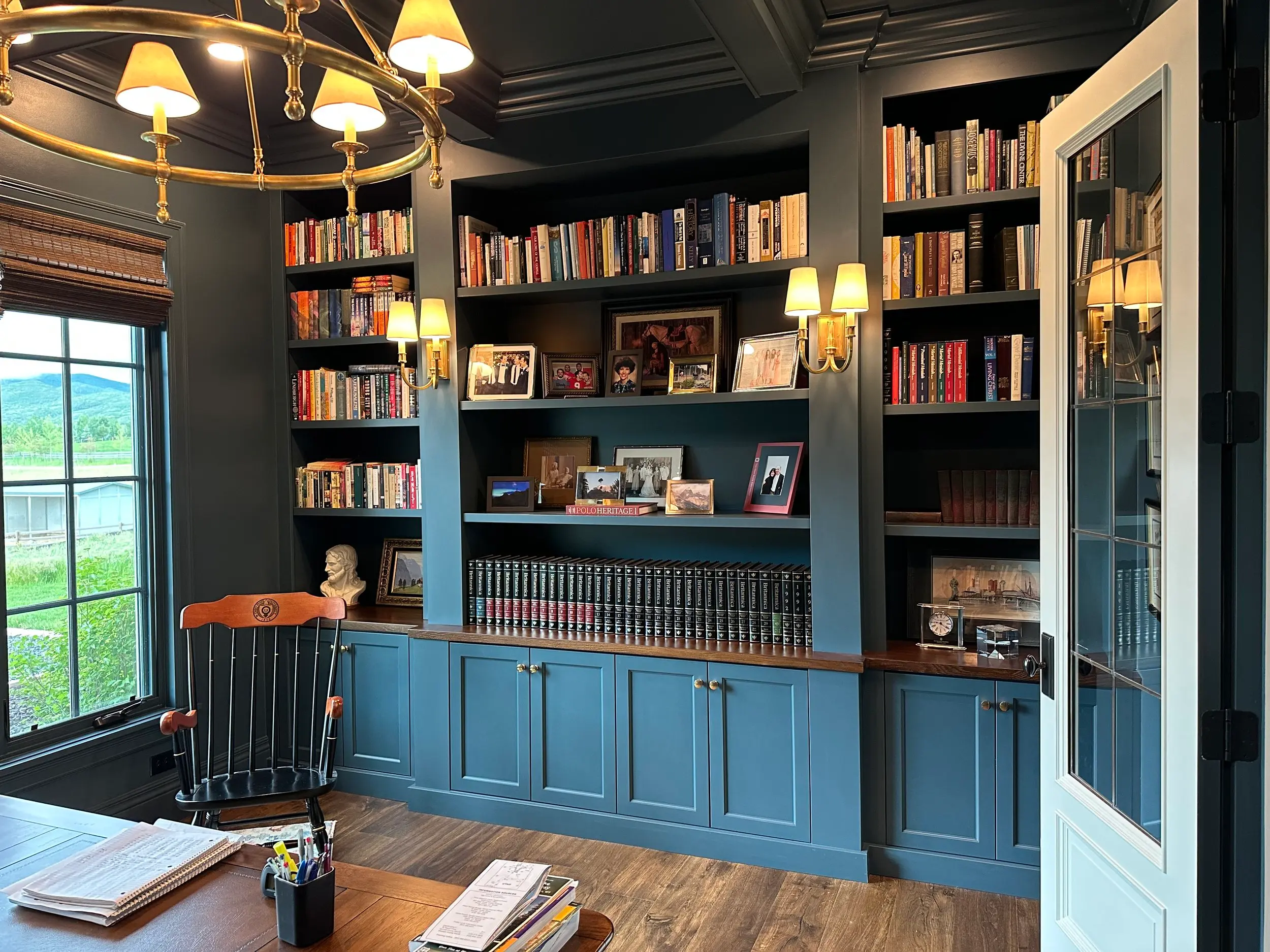 Custom home library built-ins in deep blue, featuring floor-to-ceiling bookshelves, paneled lower cabinetry, and hand-finished trim work.